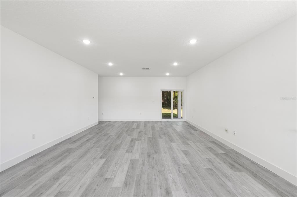 An empty, minimalist room features white walls, recessed ceiling lights, and light gray wood flooring — 820 E DESOTO STREET, CLERMONT, FL