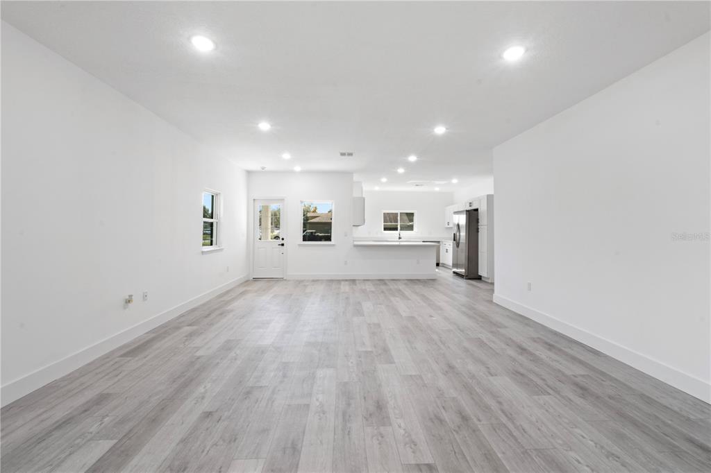 A bright, open-concept living area features white walls, recessed lighting, and light gray wood-look flooring — 820 E DESOTO STREET, CLERMONT, FL