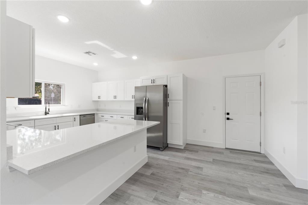 A modern kitchen features white cabinetry, stainless steel appliances, and a white quartz island countertop — 820 E DESOTO STREET, CLERMONT, FL