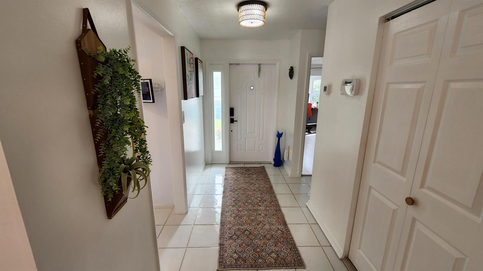 An entryway features white tile floors, a patterned runner rug, and a white front door — 1101 SW 111th Terrace, Davie FL 33324, DAVIE, FL