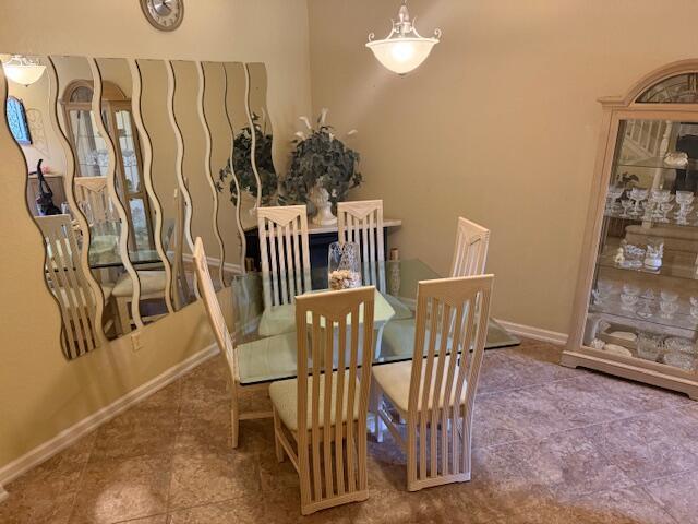 A dining room features a glass table, six chairs, a curio cabinet, and wavy wall mirrors — 3171 SW Otter Lane, Stuart FL 34997, STUART, FL