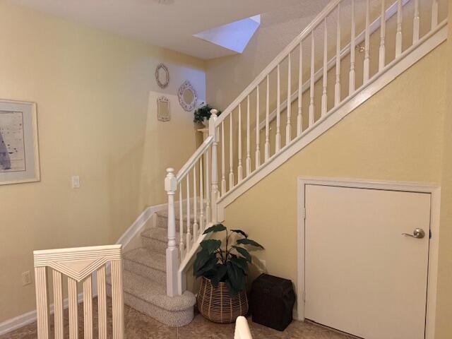 A carpeted staircase with white railings sits beside a closed door and a potted plant — 3171 SW Otter Lane, Stuart FL 34997, STUART, FL