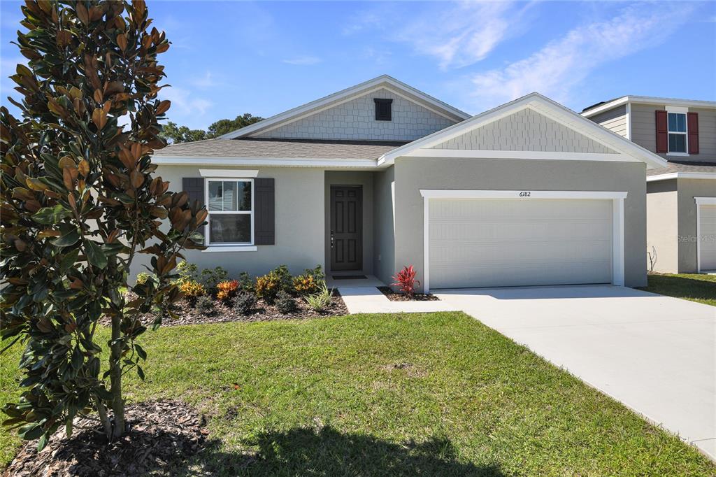 A single-story house with a gray exterior, a two-car garage, and a small front garden — 6182 SW 64TH TERRACE, OCALA, FL