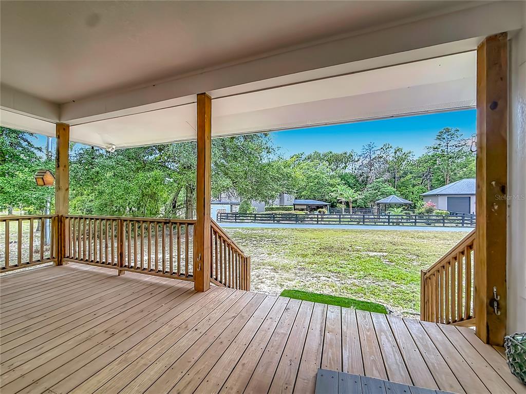A wooden deck with railings overlooks a grassy yard and a distant detached garage — 6687 W 7 RIVERS DRIVE, CRYSTAL RIVER, FL