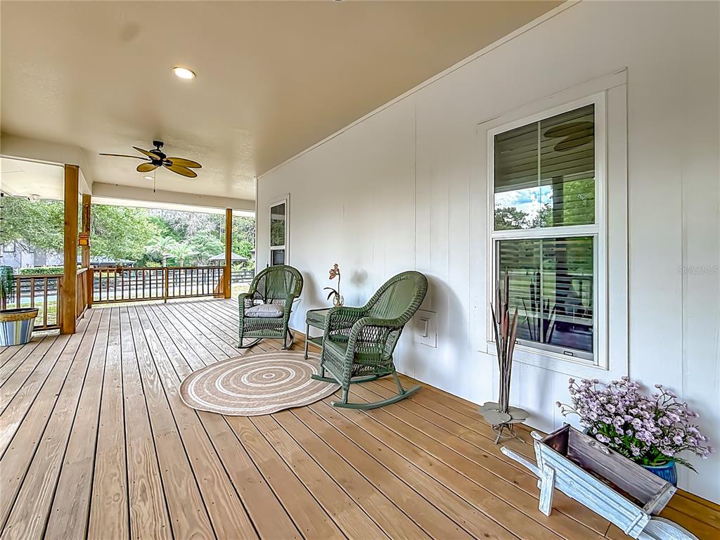 A wooden deck features two green wicker rocking chairs, a round rug, and a planter — 6687 W 7 RIVERS DRIVE, CRYSTAL RIVER, FL