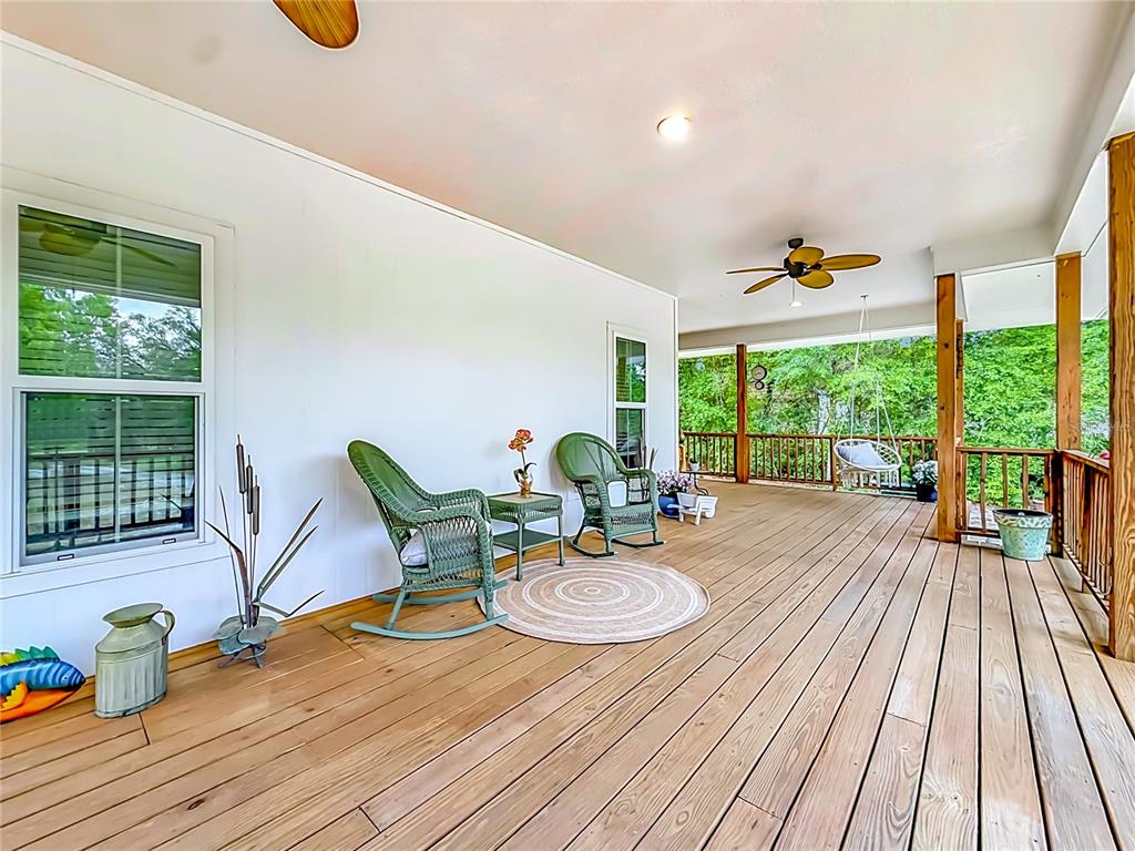 A wooden deck features two green rocking chairs, a small table, and a hanging chair — 6687 W 7 RIVERS DRIVE, CRYSTAL RIVER, FL