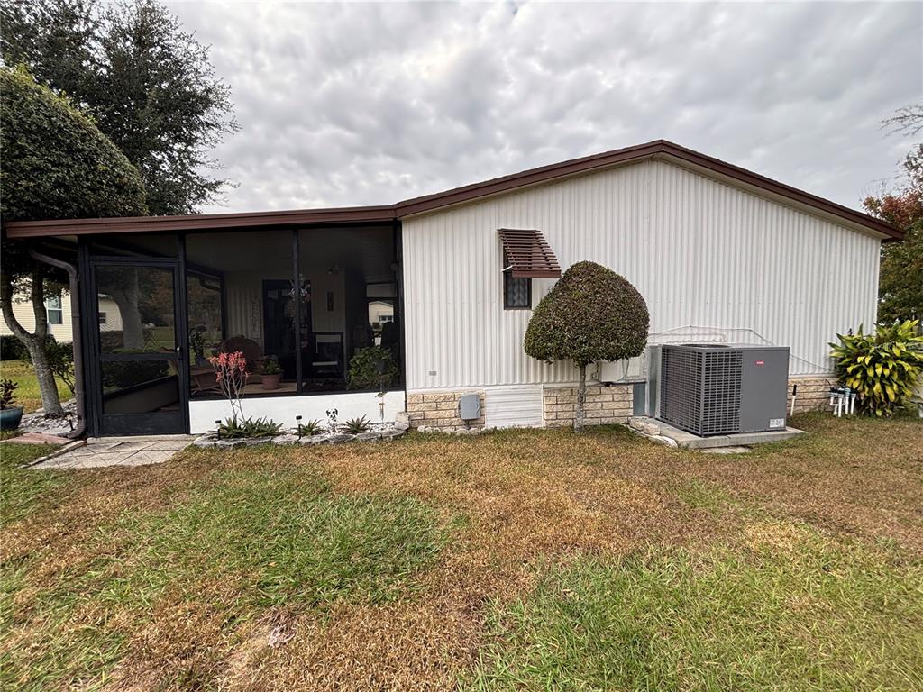 The exterior of a mobile home features a screened-in porch and a central air unit — 3833 OLAX COURT, ZELLWOOD, FL