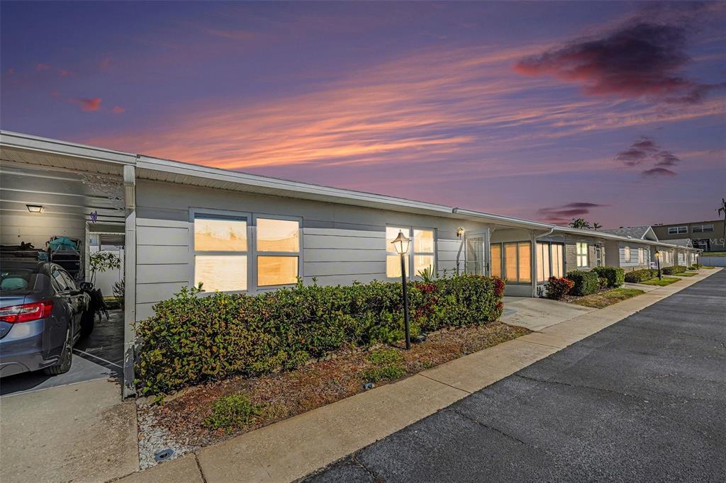 A single-story residential building with a carport, light-colored siding, and a landscaped front yard — 12400 PARK BOULEVARD UNIT 311, SEMINOLE, FL