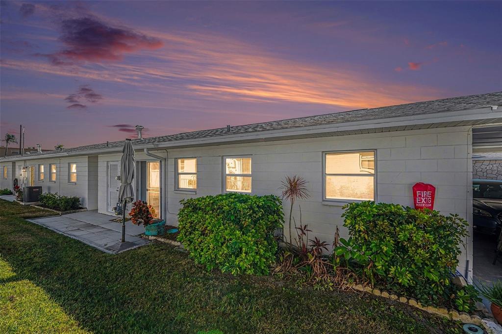 A single-story white building with a lawn, landscaping, and a sunset sky — 12400 PARK BOULEVARD UNIT 311, SEMINOLE, FL