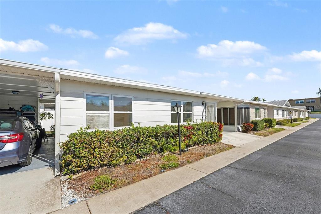 A single-story residential building with a carport, white siding, and a landscaped front yard — 12400 PARK BOULEVARD UNIT 311, SEMINOLE, FL