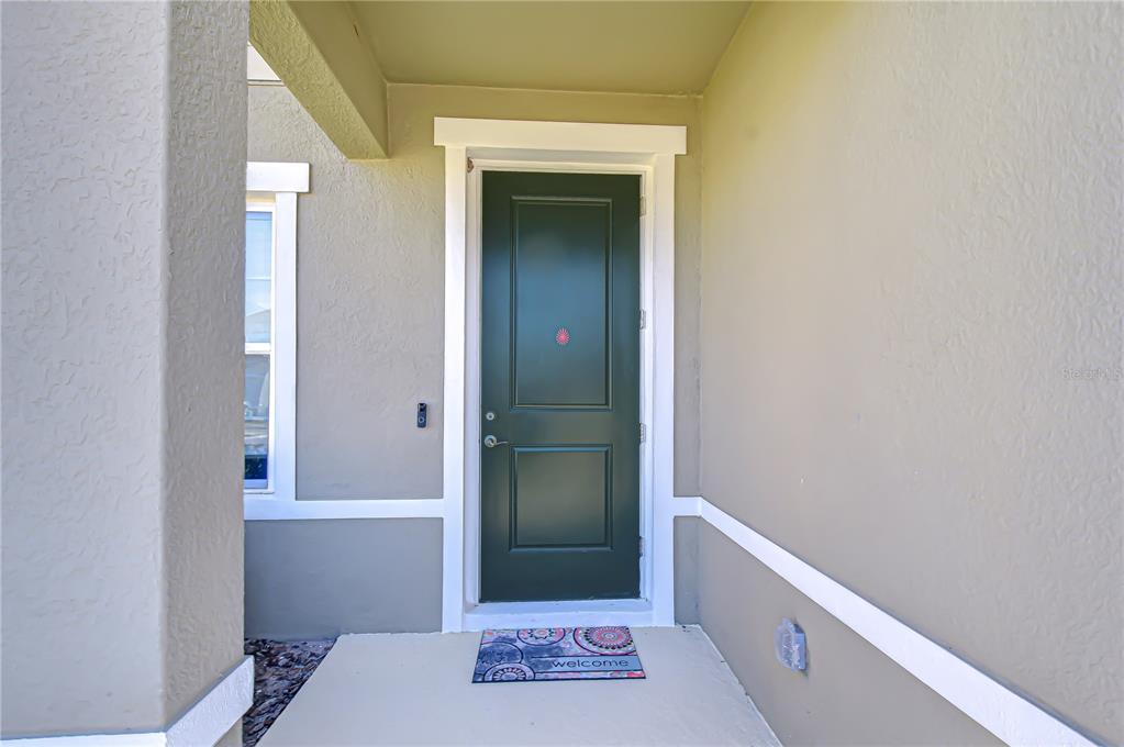 A dark green front door with white trim sits under a covered entryway — 10422 GLIDING EAGLE WAY, LAND O LAKES, FL