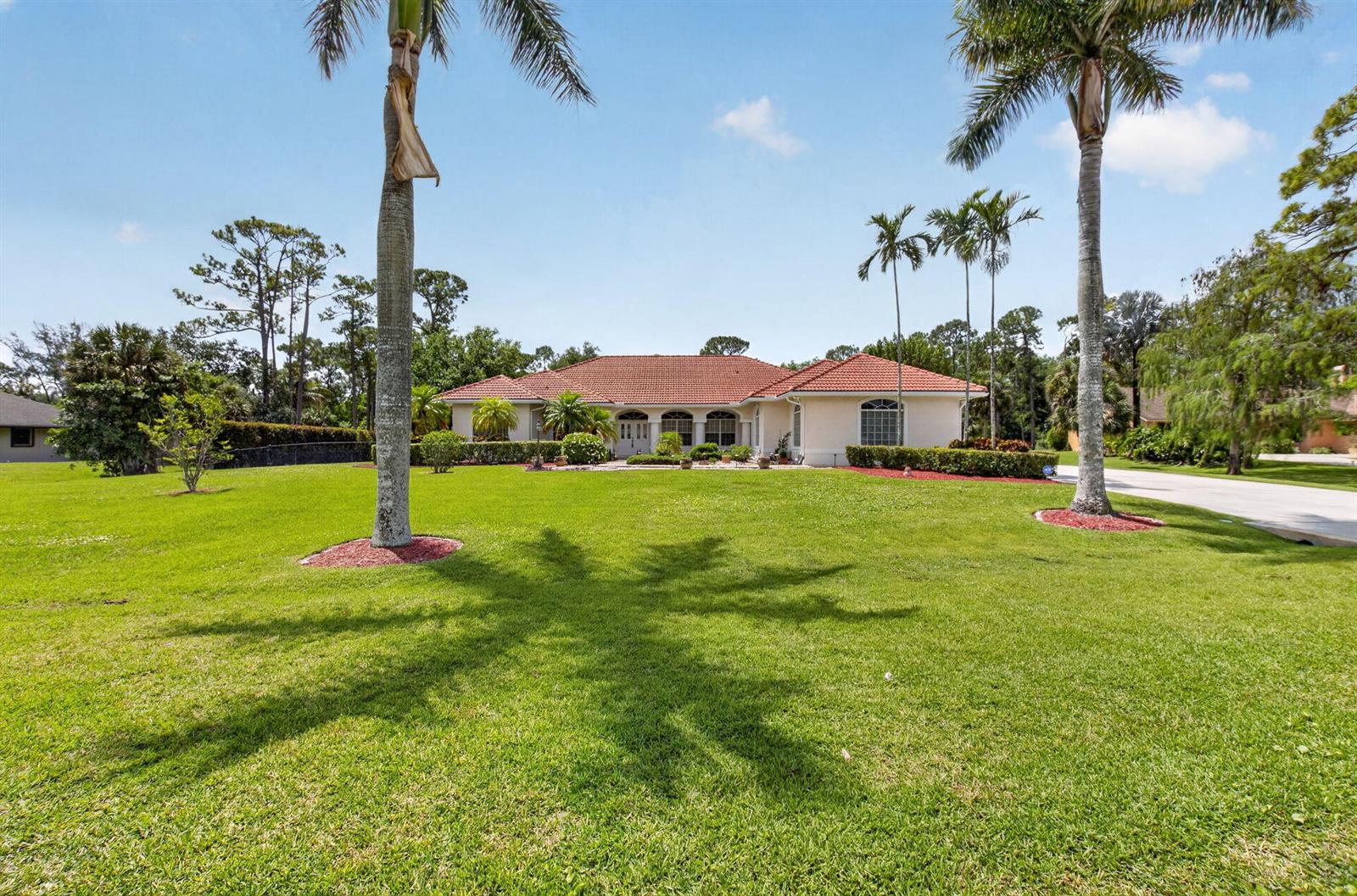 A single-story house with a red tile roof sits behind a large green lawn — 9774 Saddle Court, Lake Worth FL 33467, LAKE WORTH, FL