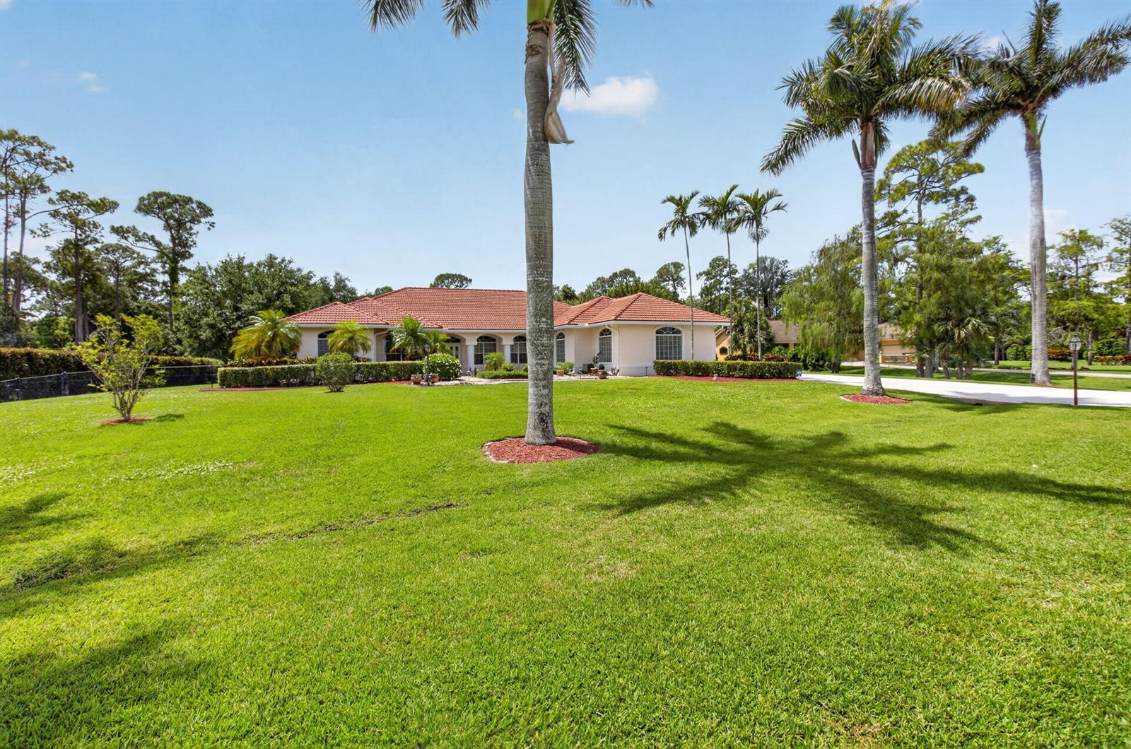 A single-story house with a red tile roof sits behind a large, grassy front lawn — 9774 Saddle Court, Lake Worth FL 33467, LAKE WORTH, FL