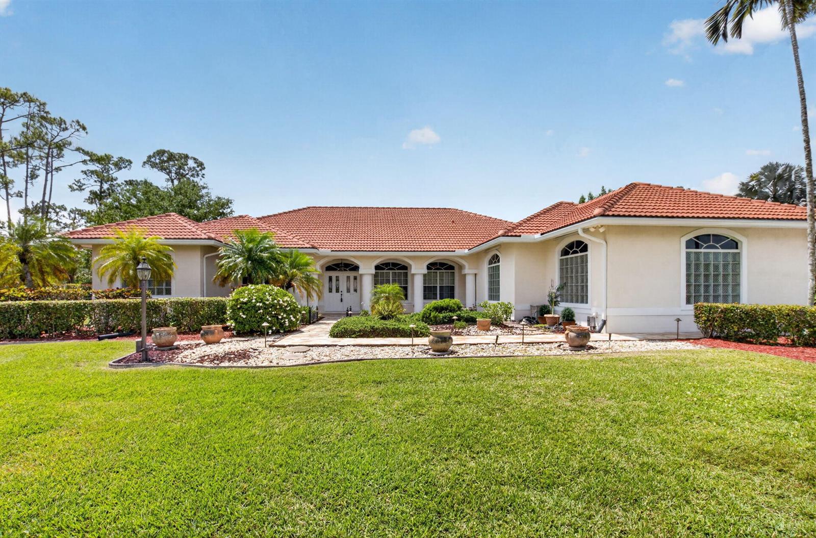 A single-story house with a red tile roof, beige stucco exterior, and a landscaped yard — 9774 Saddle Court, Lake Worth FL 33467, LAKE WORTH, FL