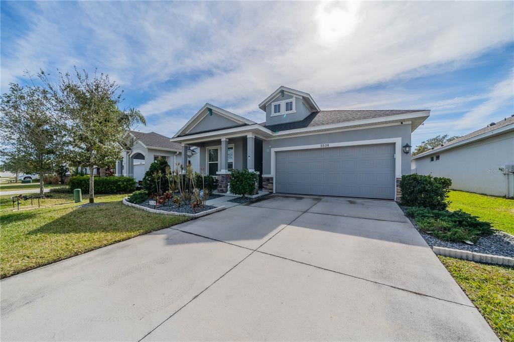 A gray single-story house with a two-car garage and a small front garden — 5538 SPANISH MOSS COVE, BRADENTON, FL