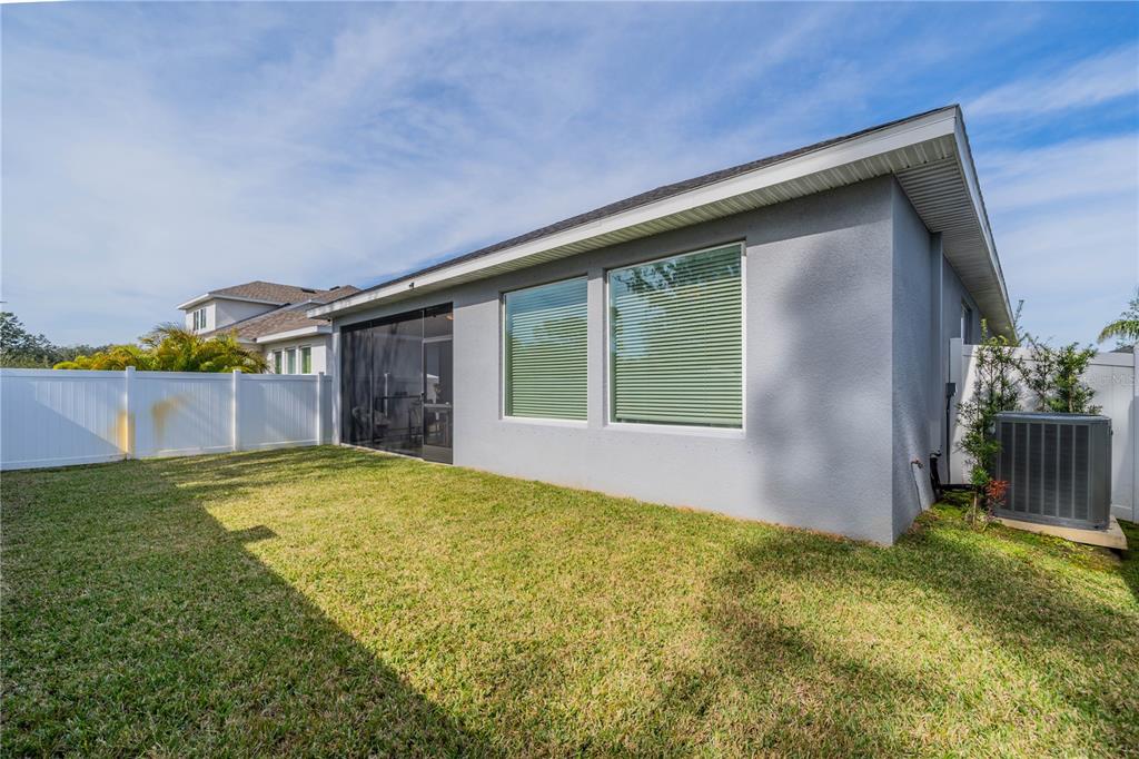 The exterior of a gray house features a screened-in patio and a fenced backyard — 5538 SPANISH MOSS COVE, BRADENTON, FL