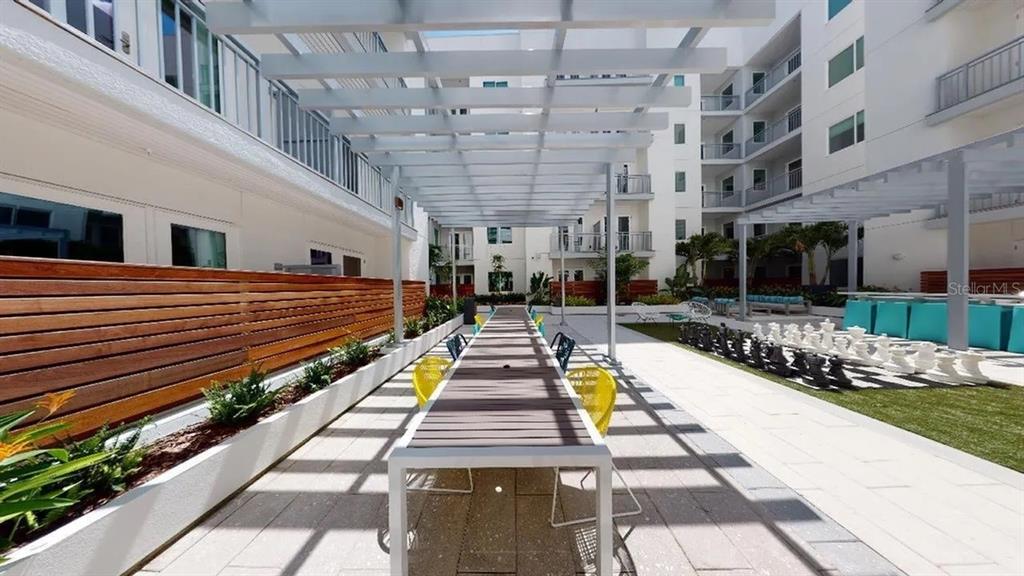 An outdoor courtyard features a long dining table under a pergola and a giant chessboard — 505 CHATHAM AVENUE, ORLANDO, FL