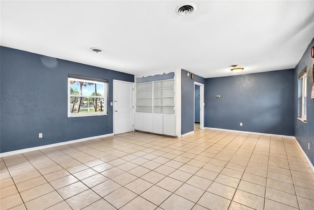 A living room with blue walls, tile flooring, a white built-in bookshelf, and a door — 2622 SW 35TH AVENUE, OCALA, FL