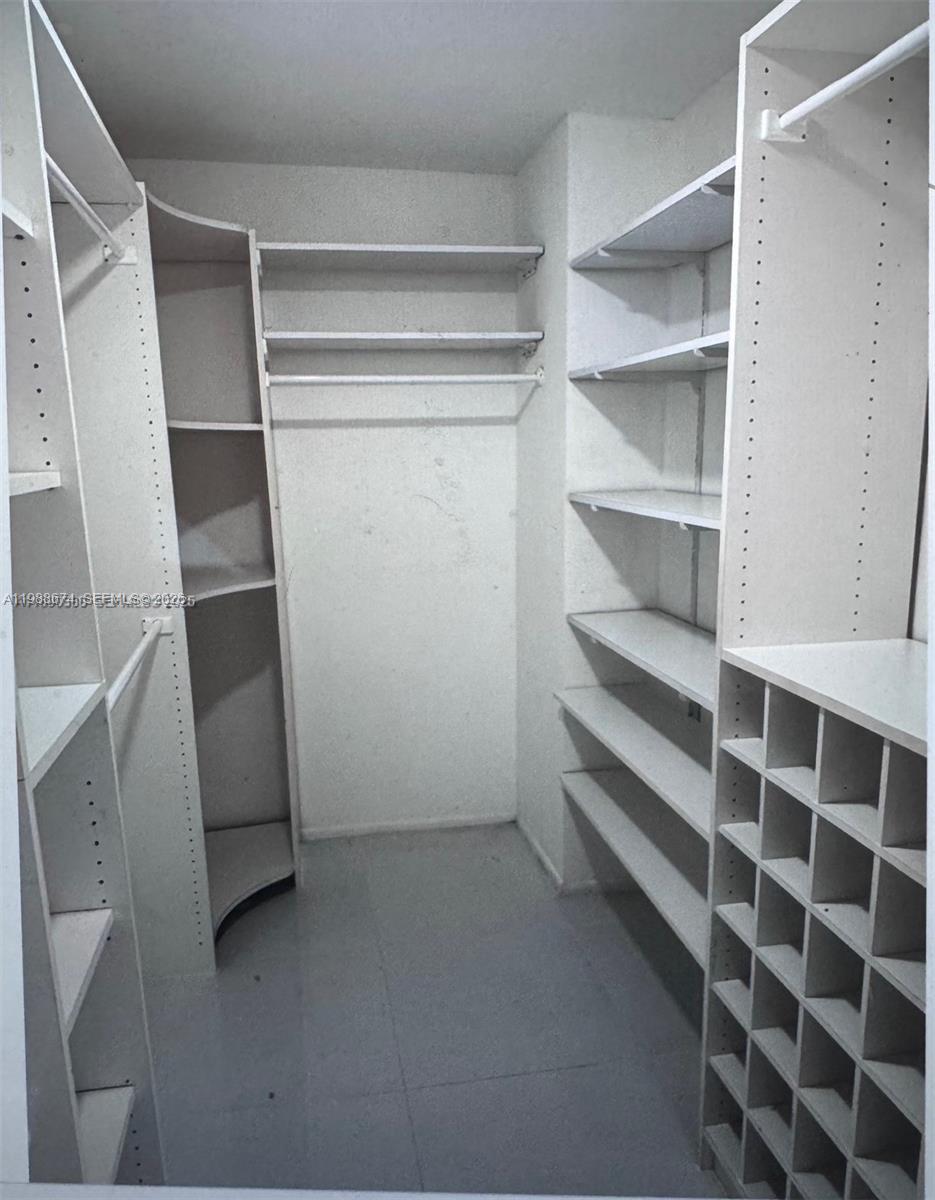 A walk-in closet features white shelving, a shoe rack, and hanging rods on the walls — 4000 Towerside Ter # 609, Miami FL 33138, MIAMI, FL
