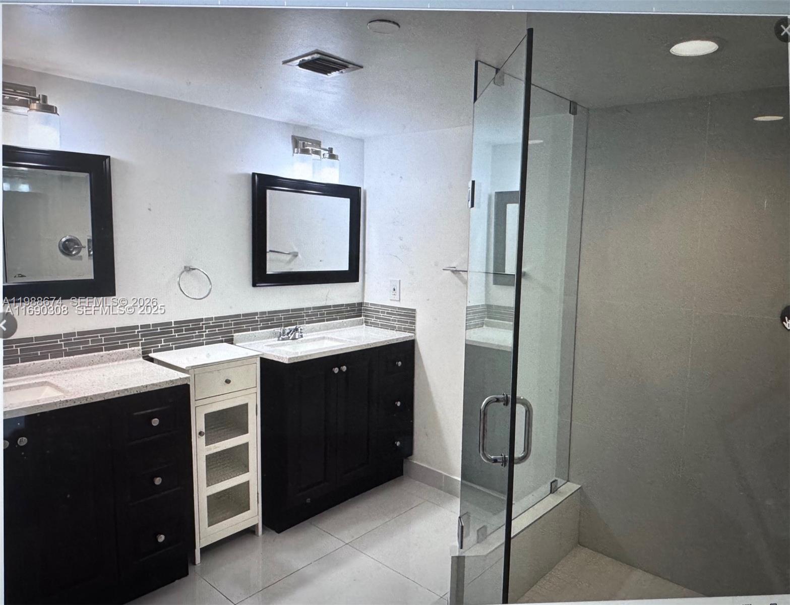 A bathroom features a double vanity with dark cabinets, white countertops, and a glass-enclosed shower — 4000 Towerside Ter # 609, Miami FL 33138, MIAMI, FL