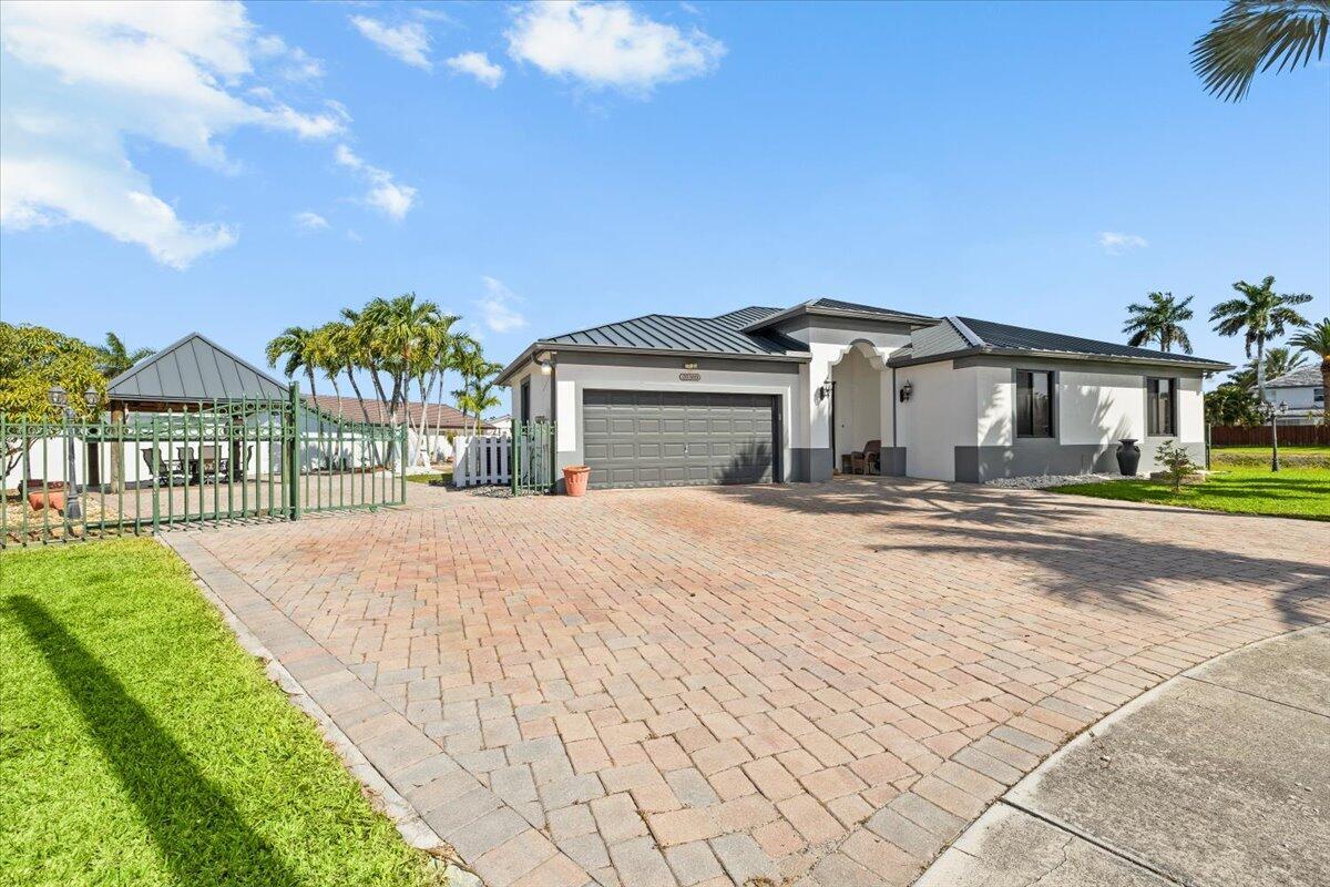 A single-story house with a paved driveway, a two-car garage, and a green metal fence — 20300 SW 129th Place, Miami FL 33177, MIAMI, FL