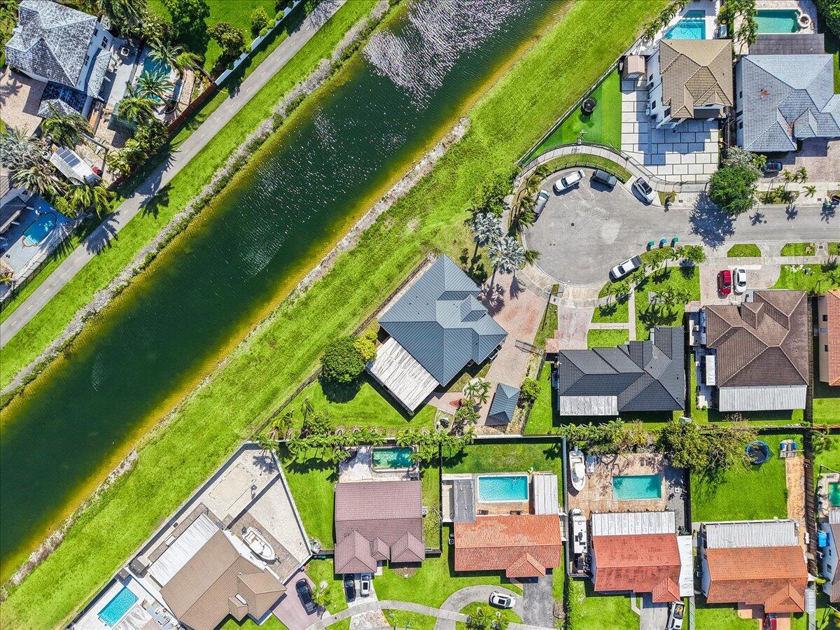 An aerial view shows a suburban neighborhood with houses, swimming pools, and a canal — 20300 SW 129th Place, Miami FL 33177, MIAMI, FL