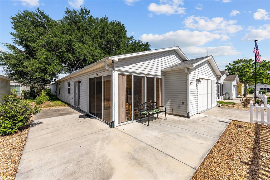 A light-colored house with a concrete patio, sliding glass doors, and an attached garage — 1710 ROSALES ROAD, THE VILLAGES, FL