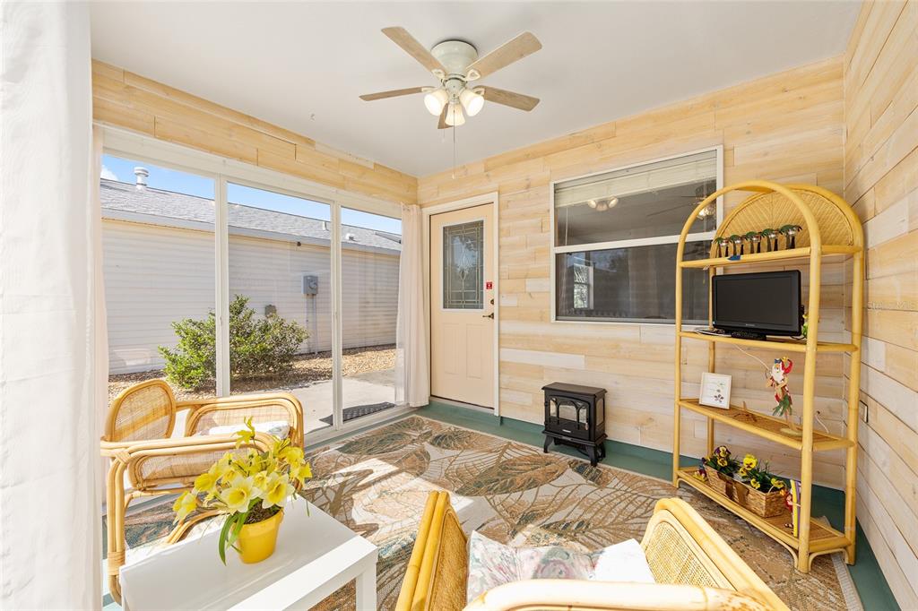 A sunroom features light wood-paneled walls, a ceiling fan, wicker furniture, and a rug — 1710 ROSALES ROAD, THE VILLAGES, FL