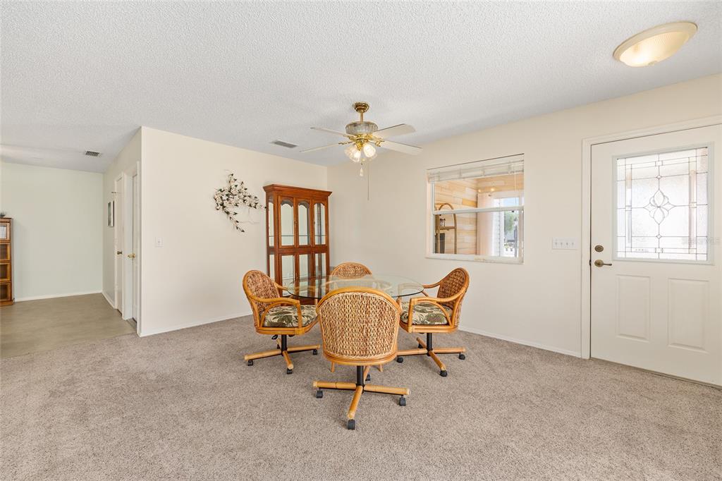 A dining area features a glass-topped table, four wicker chairs, and a wooden china cabinet — 1710 ROSALES ROAD, THE VILLAGES, FL