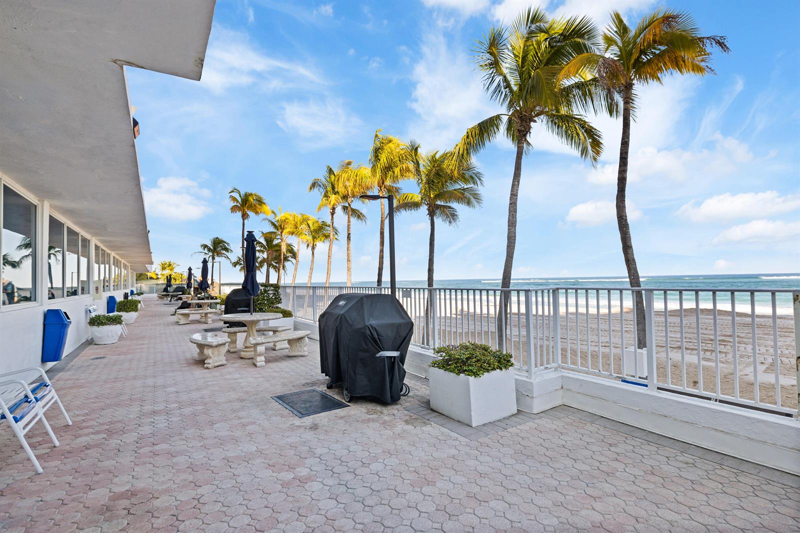A paved patio features outdoor grills, seating, and palm trees overlooking a sandy beach — 1360 S Ocean Boulevard # 403, Pompano Beach FL 33062, POMPANO BEACH, FL