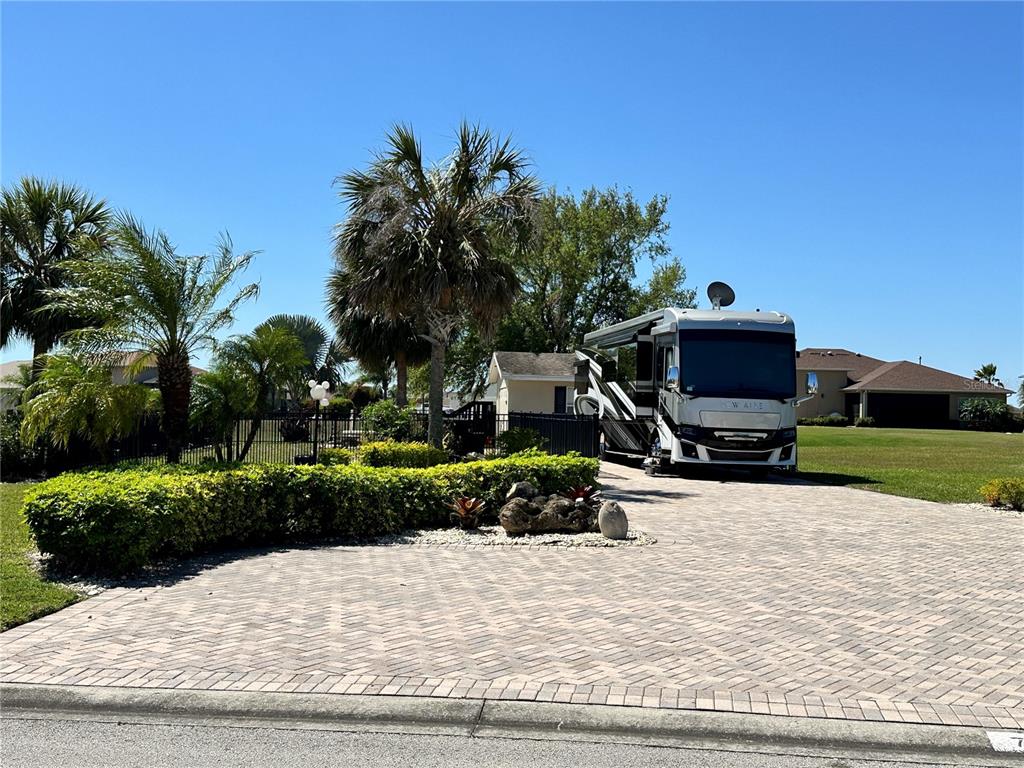 A large recreational vehicle is parked on a paved driveway in front of a house — 728 TEABERRY TRAIL, POLK CITY, FL