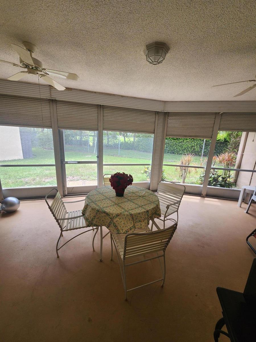 A screened-in patio features a round table, metal chairs, and a ceiling fan — 4821 NW 13th Avenue, Deerfield Beach FL 33064, DEERFIELD BEACH, FL