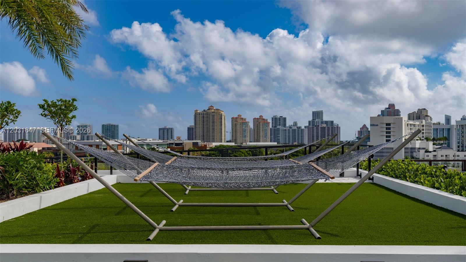 A rooftop terrace features two hammocks on metal stands over artificial turf with city views — 19401 W Dixie Hwy # 313, Miami FL 33180, MIAMI, FL