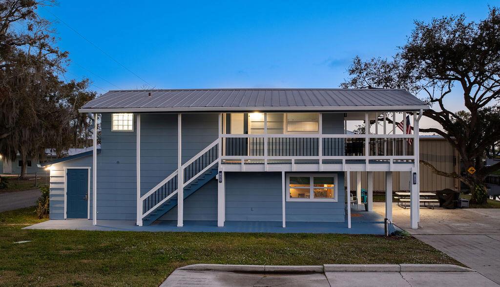 A blue two-story house with a metal roof, an elevated porch, and an exterior staircase — 1020 4th Street, Okeechobee FL 34974, OKEECHOBEE, FL