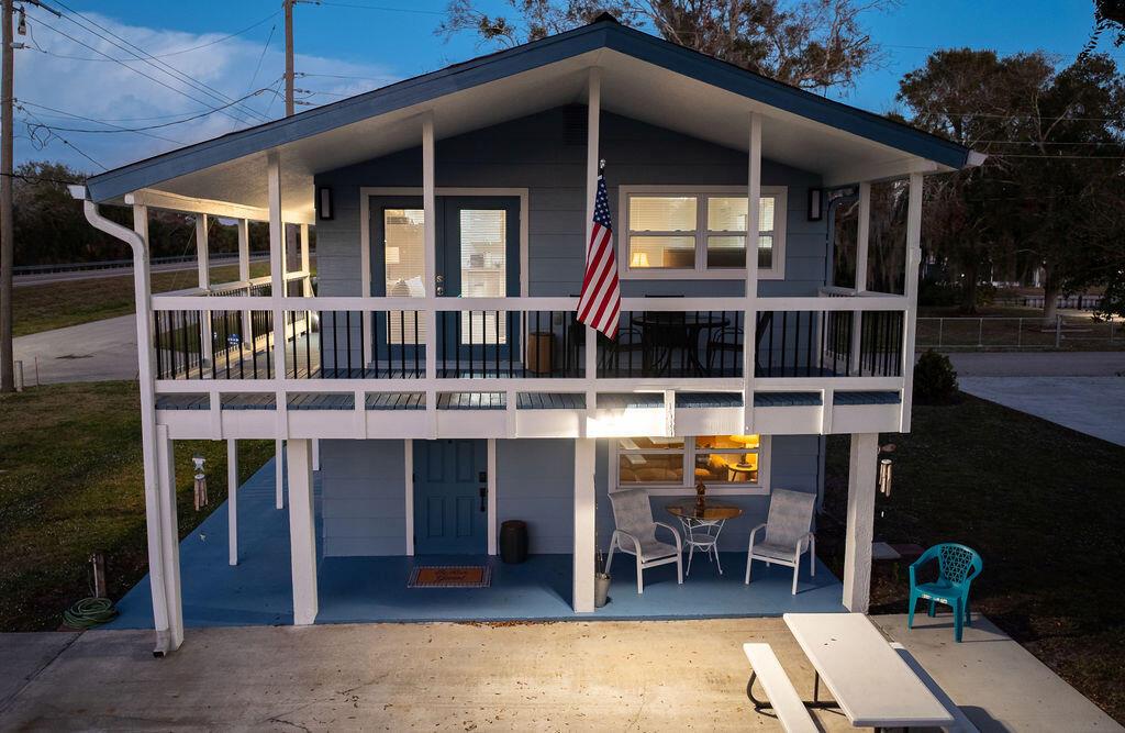A two-story blue house with a covered porch, balcony, and an American flag — 1020 4th Street, Okeechobee FL 34974, OKEECHOBEE, FL