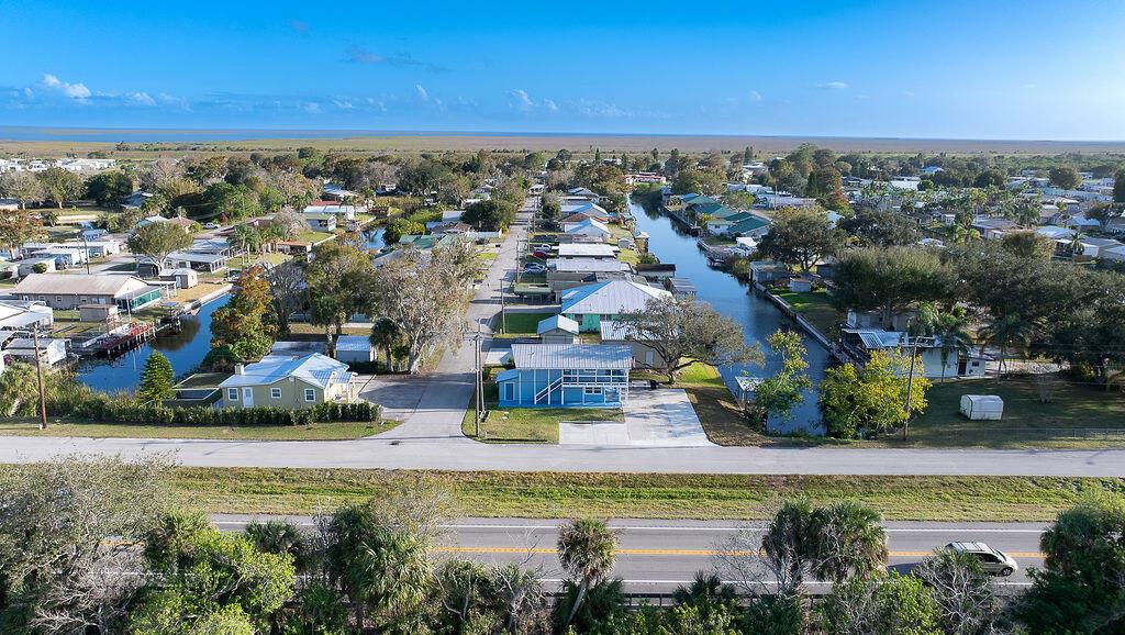 An aerial view shows a residential neighborhood with houses situated along canals near a highway — 1020 4th Street, Okeechobee FL 34974, OKEECHOBEE, FL