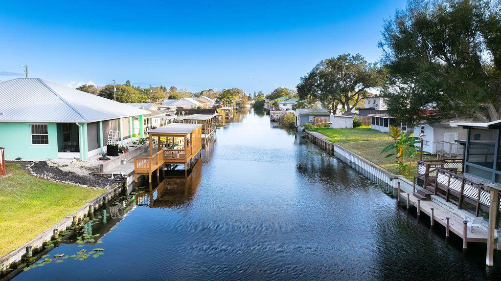 A canal flows between houses with wooden docks and screened porches under a blue sky — 1020 4th Street, Okeechobee FL 34974, OKEECHOBEE, FL