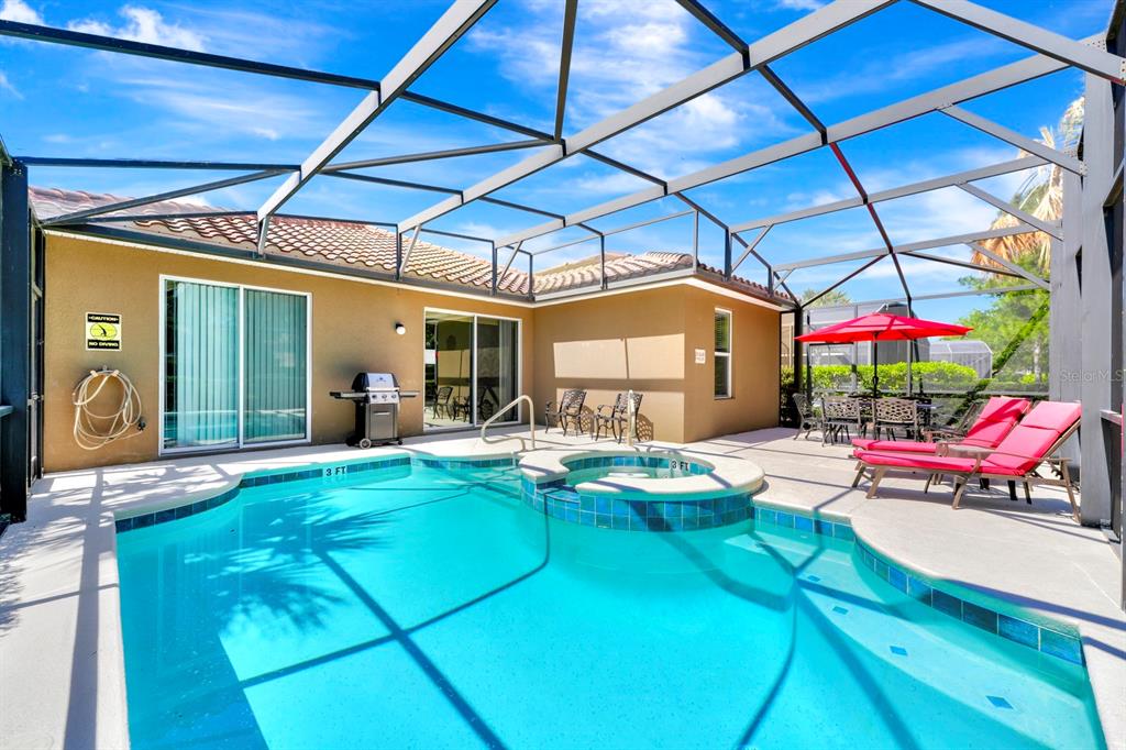 A swimming pool and hot tub are enclosed within a screened-in patio area — 4416 ACORN COURT, DAVENPORT, FL