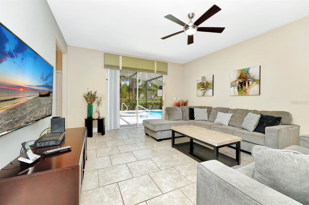 A living room features a large sectional sofa, tile flooring, and a sliding glass door — 4416 ACORN COURT, DAVENPORT, FL