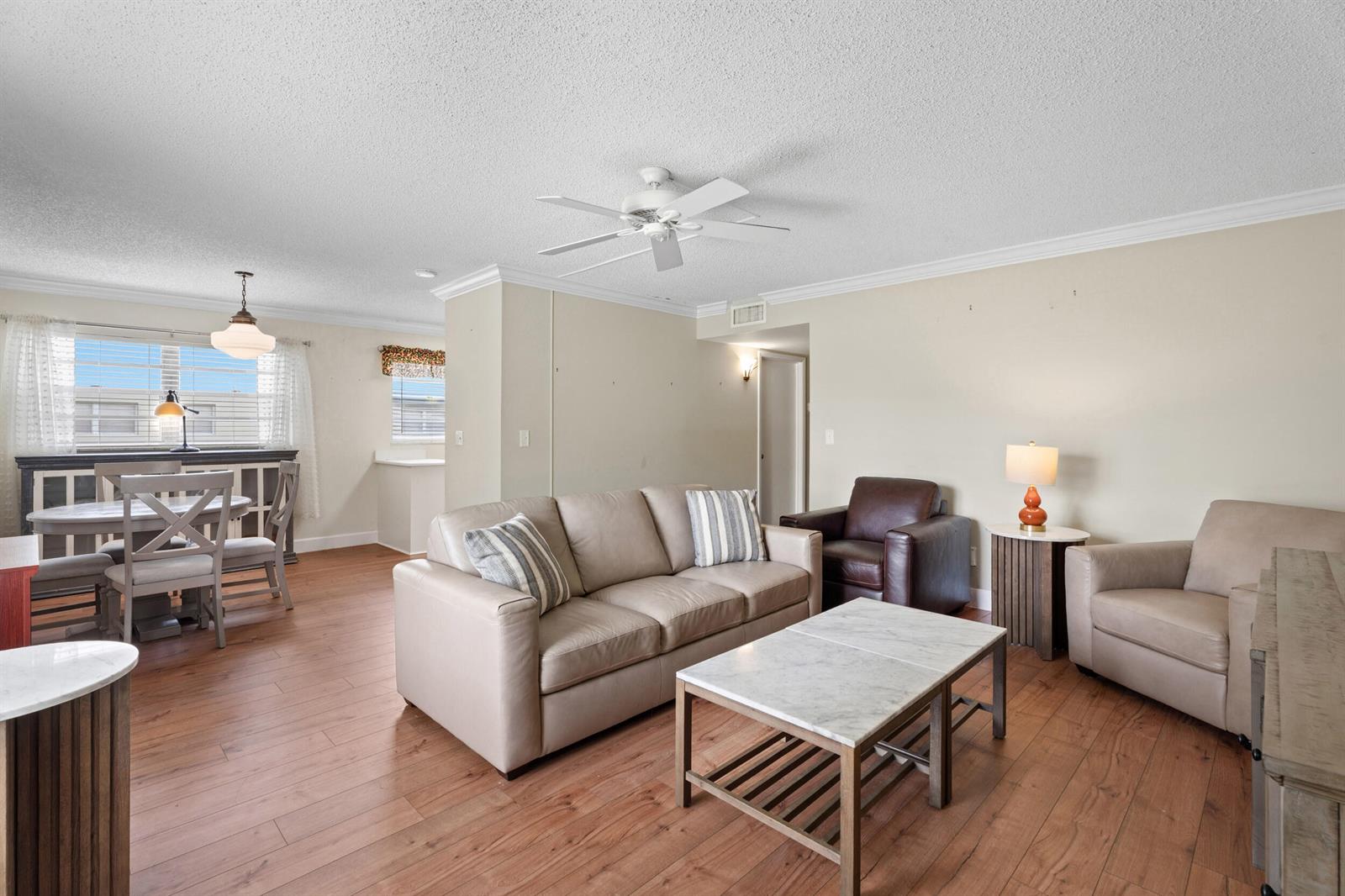 A living room with light-colored furniture, a marble coffee table, and wood-look flooring — 33 Pine Arbor Lane # 102, Vero Beach FL 32962, VERO BEACH, FL