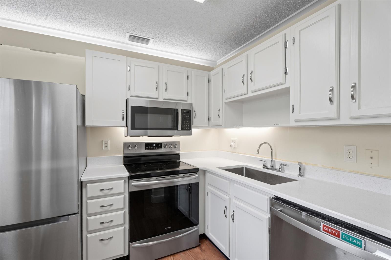 A kitchen features white cabinets, stainless steel appliances, and white countertops — 33 Pine Arbor Lane # 102, Vero Beach FL 32962, VERO BEACH, FL