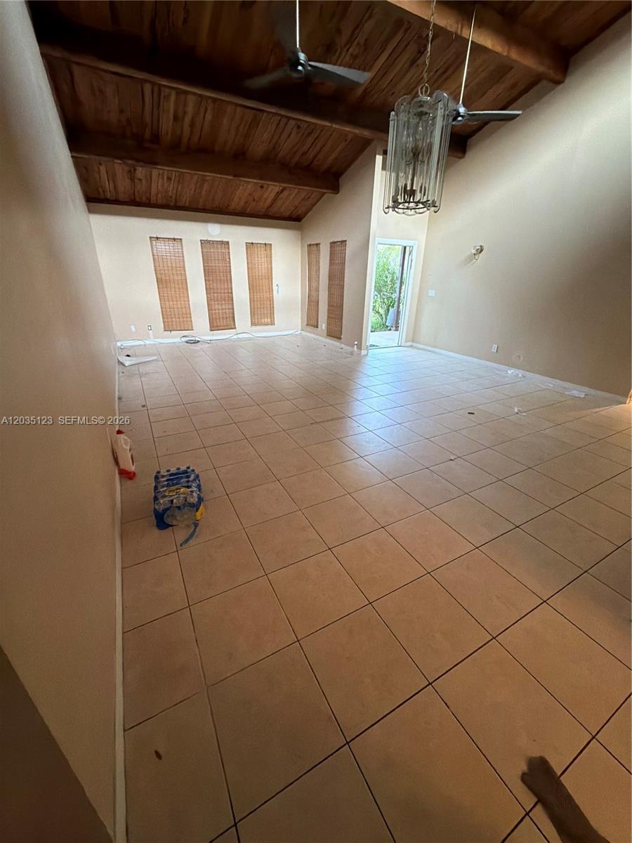 A spacious living room features vaulted wood-paneled ceilings, tile flooring, and a hanging chandelier — 3603 W Wilderness Dr W, Fort Pierce FL 34982, FORT PIERCE, FL