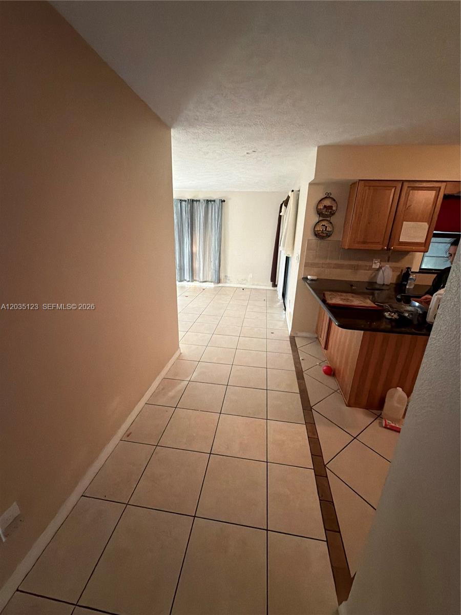 A tiled hallway leads from the foreground toward a living area with a kitchen nearby — 3603 W Wilderness Dr W, Fort Pierce FL 34982, FORT PIERCE, FL
