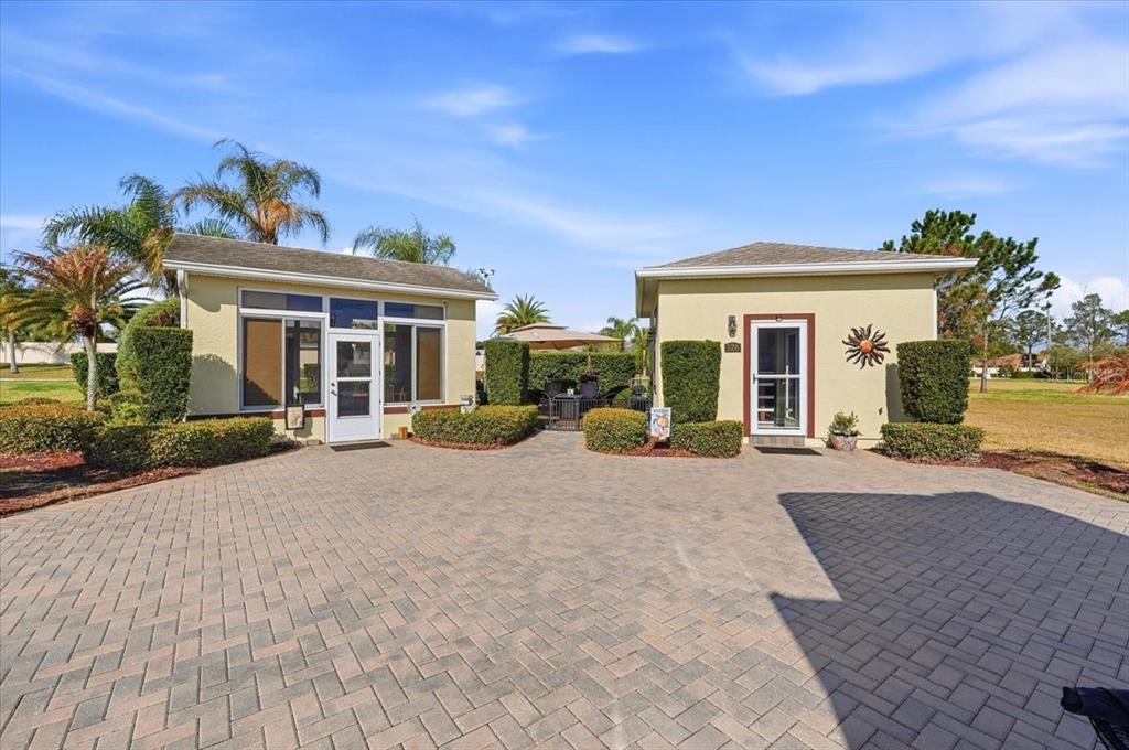 Two small, light-colored buildings with a paved courtyard and patio furniture between them — 326 NOLANE LANE, POLK CITY, FL