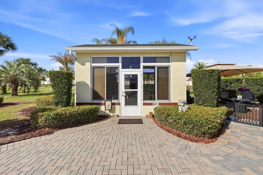 A small, detached building with a white door and large windows sits on a patio — 326 NOLANE LANE, POLK CITY, FL