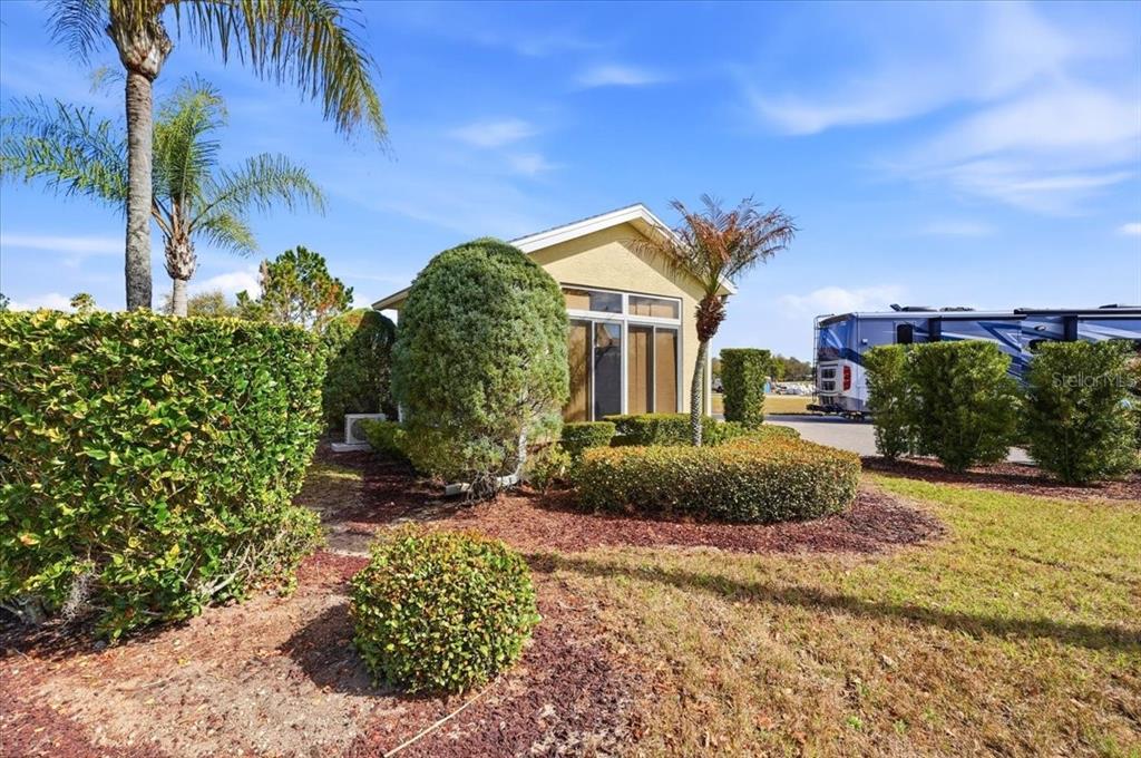 A small, tan-colored house with a large glass sliding door is surrounded by manicured landscaping — 326 NOLANE LANE, POLK CITY, FL