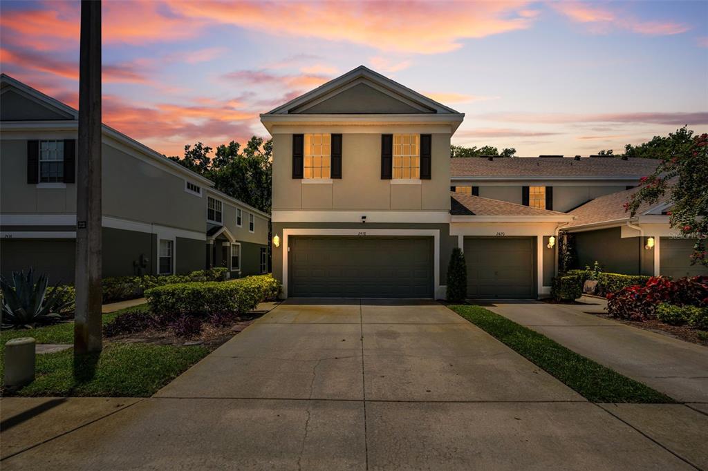 A two-story townhome with a two-car garage and a concrete driveway at sunset — 2418 EARLSWOOD COURT, BRANDON, FL