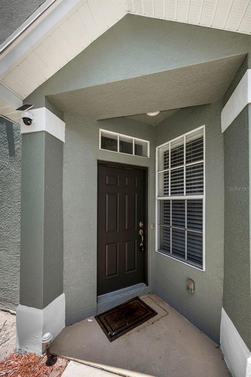 The exterior entrance features a dark brown door, a window with blinds, and a security camera — 2418 EARLSWOOD COURT, BRANDON, FL