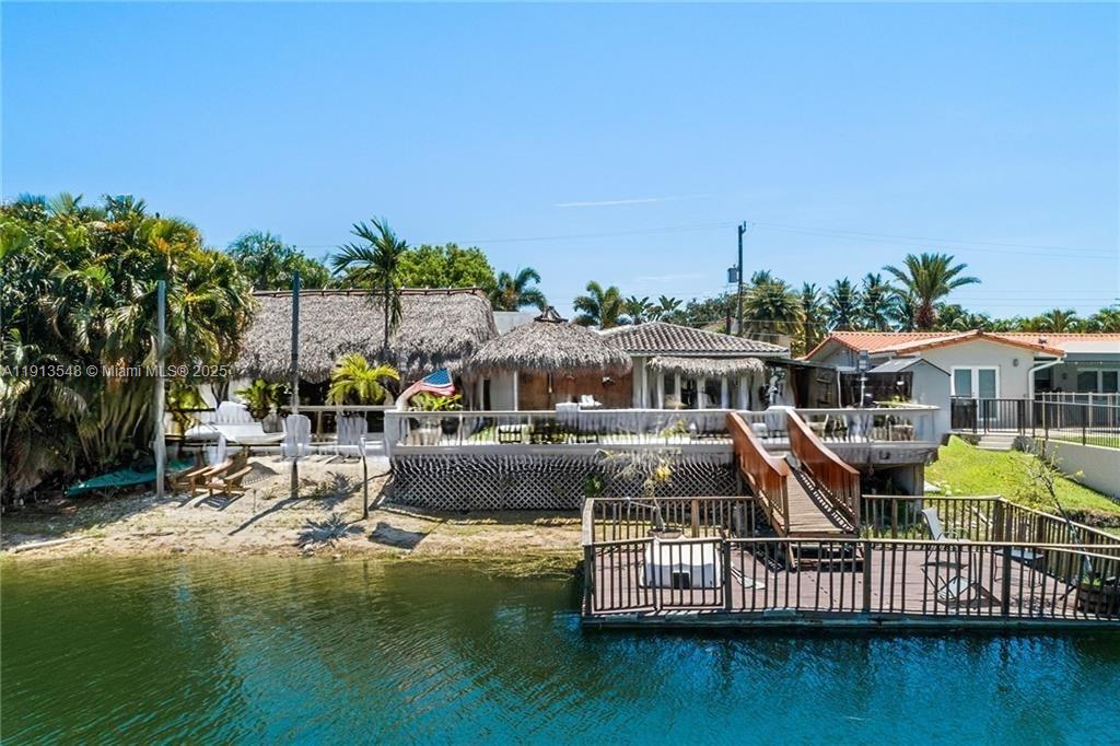 A waterfront house features a thatched roof, a wooden deck, and a private dock — 21280 NE 23rd Ave, Miami FL 33180, MIAMI, FL
