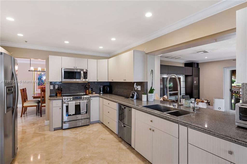 A kitchen features light-colored cabinets, stainless steel appliances, and dark granite countertops — 21280 NE 23rd Ave, Miami FL 33180, MIAMI, FL